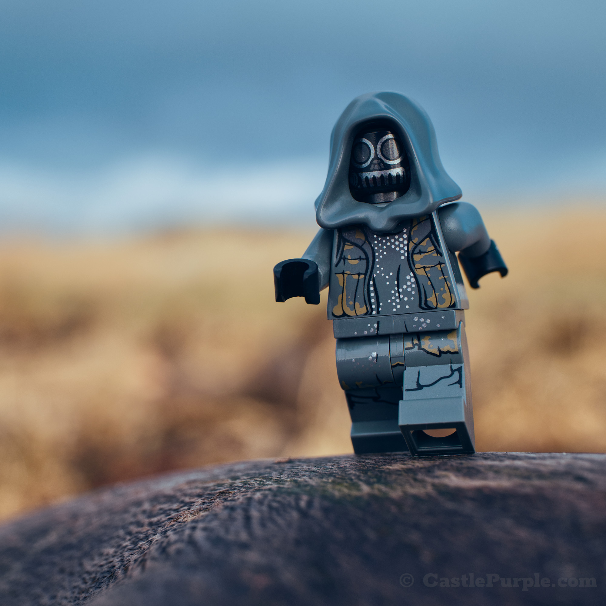 Unkar's Thug Lego minifigure walking with yellow-ish grass and a blue sky in the distance
